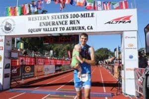 Coach Andrew Taylor holding Samuel at the finish line of the Western States 100