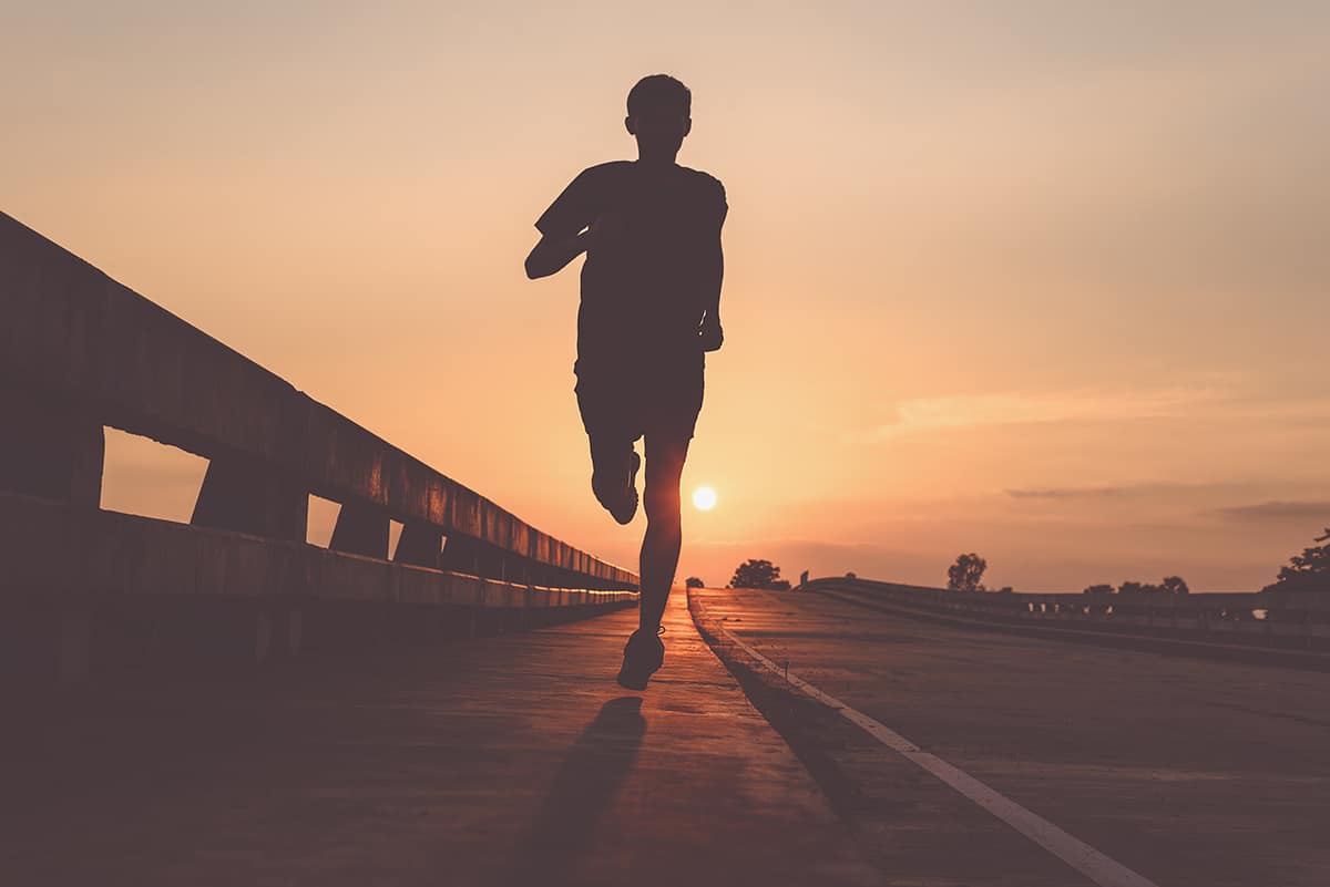 Motivational Running Quotes featured image of runner running on road during sunset
