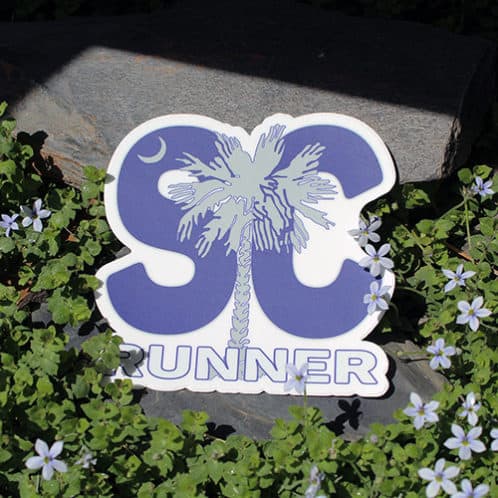 South Carolina Running Sticker laying on rocks with white flowers for website
