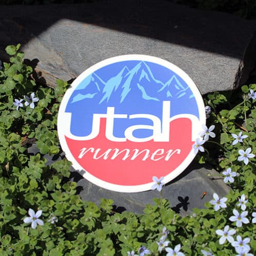 Utah Running Sticker laying on rocks with white flowers for website