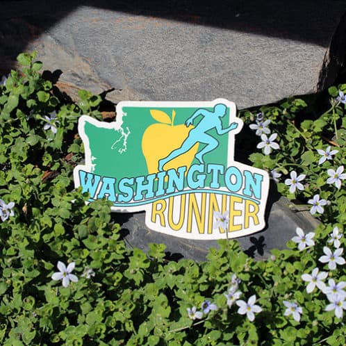 Washington Running Sticker laying on rocks with white flowers for website