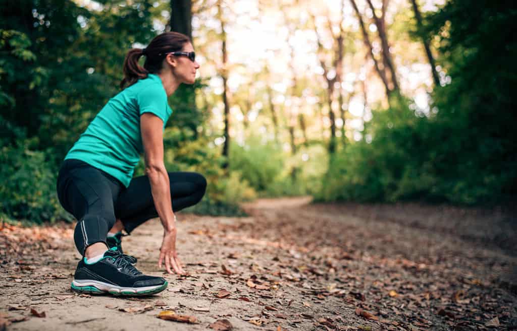 Woman stretching on a trail illustrating should eat before running