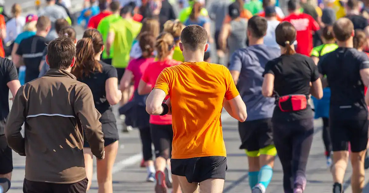 Pack of runners mid-race checking pace on a GPS watch, illustrating race-day pacing strategy