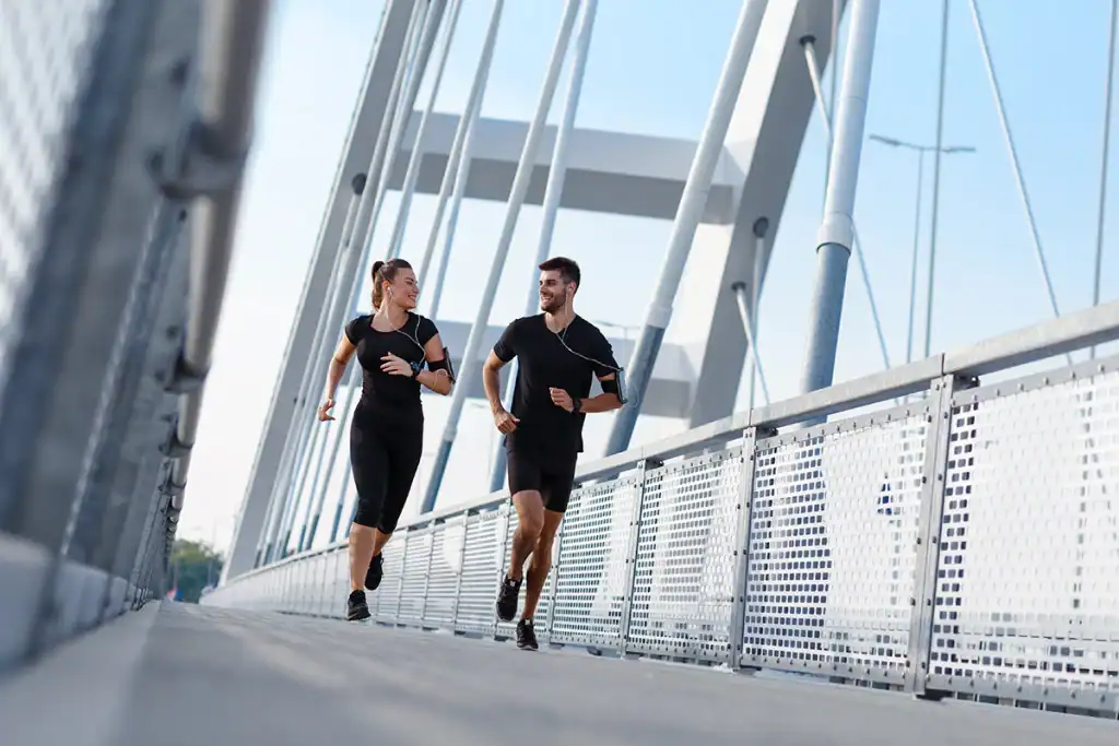 couple running on a bridge while completing an advanced 5k training plan