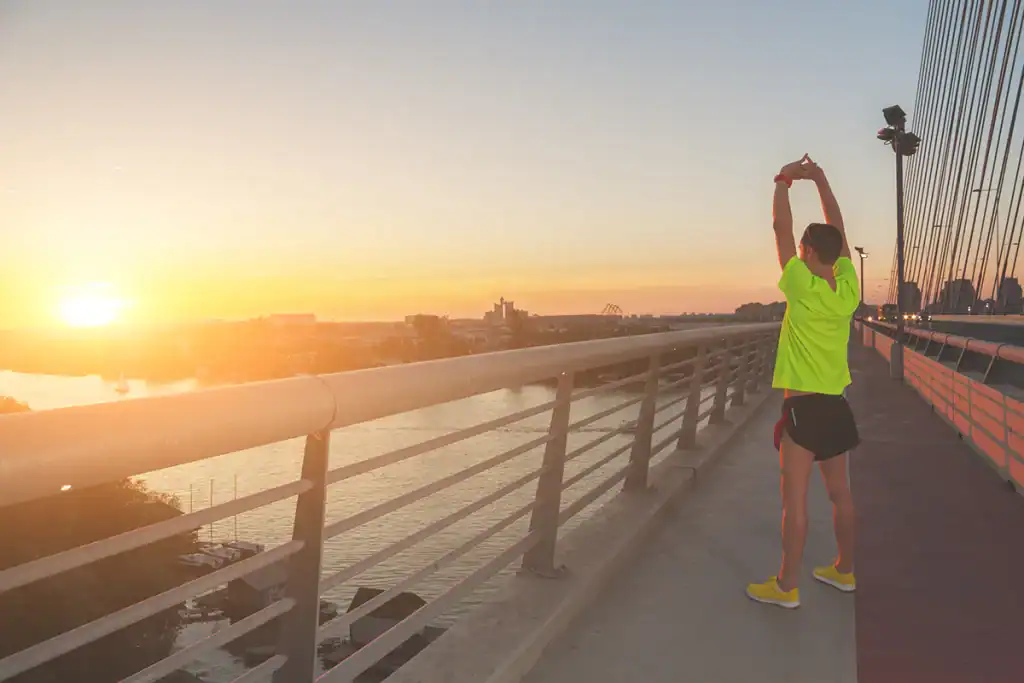 intermediate half marathon to marathon bridge plan runner stretching on bridge